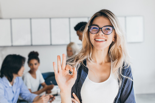 Femme disant que tout est OK devant une équipe travaillant sur une table dans un bureau moderne