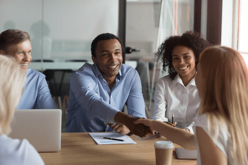 Des personnes autour d'une table se serrent la main pour exprimer leur accord en entreprise.