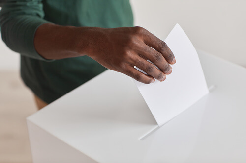 Un homme met un bulletin de vote dans une urne.