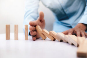 Un homme stoppe un domino en interposant sa main. C'est une métaphore du droit d'alerte économique du CSE.