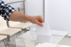 Un homme tient un bulletin de vote au dessus d'une urne.