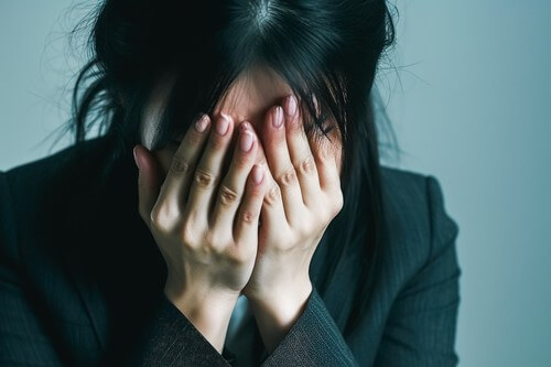 Femme se couvrant le visage avec les mains, exprimant la détresse.