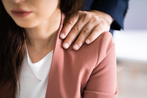 Un homme harcèle une femme en posant sa main sur son épaule.